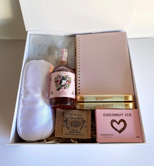 52 week spiral bound planner, Coconut ice, White satin eye mask, Imagination raspberry gin 200ml bottle, Panna pnk clay vegan soap, Glow lab face sheet mask, 2x Whittakers white chocolate sante bars. All packaged in a magnetic box with ribbon and personalized message. Gratefully gifted christchurch new zealand 